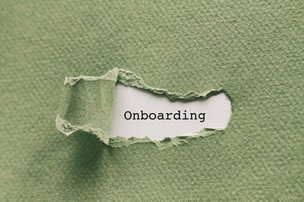 Photo of a piece of green paper. A small portion of the paper is ripped and pulled back in the center, revealing the word "onboarding" underneath.